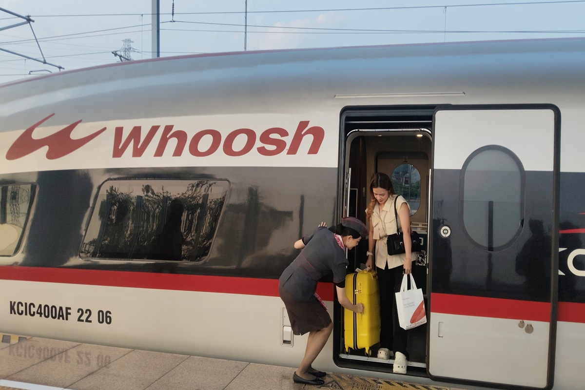 Seorang petugas Kereta membantu menurunkan barang milik penumpang Kereta Cepat Whoosh. Kamis (31/7/2025).(Solopos/Fitroh Nurikhsan)