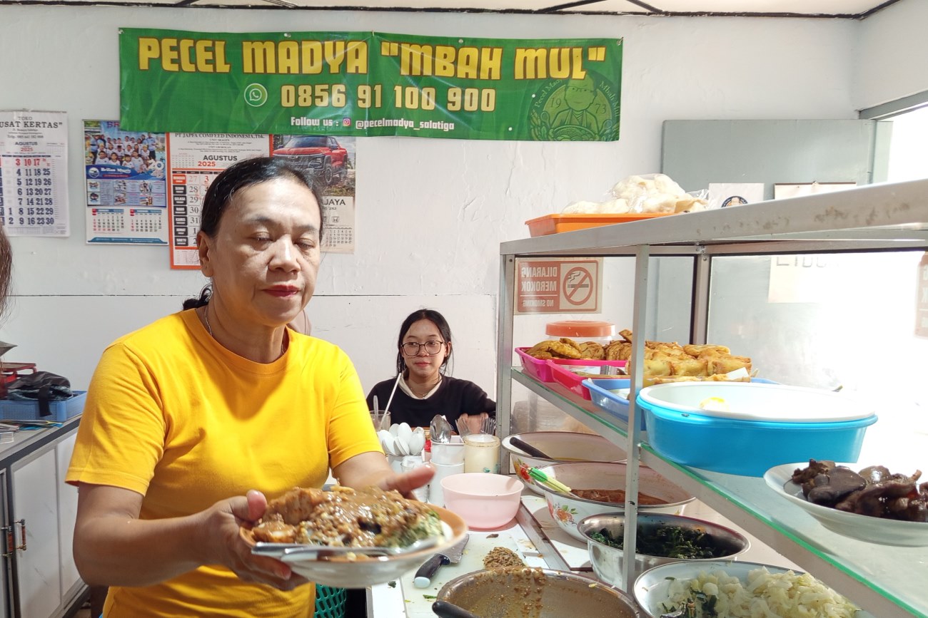 Pemilik Pecel Madya Mbah Mul, Siwi, menyajikan pecel untuk pelanggan, Sabtu (16/8/2025). (Solopos/Hawin Alaina)