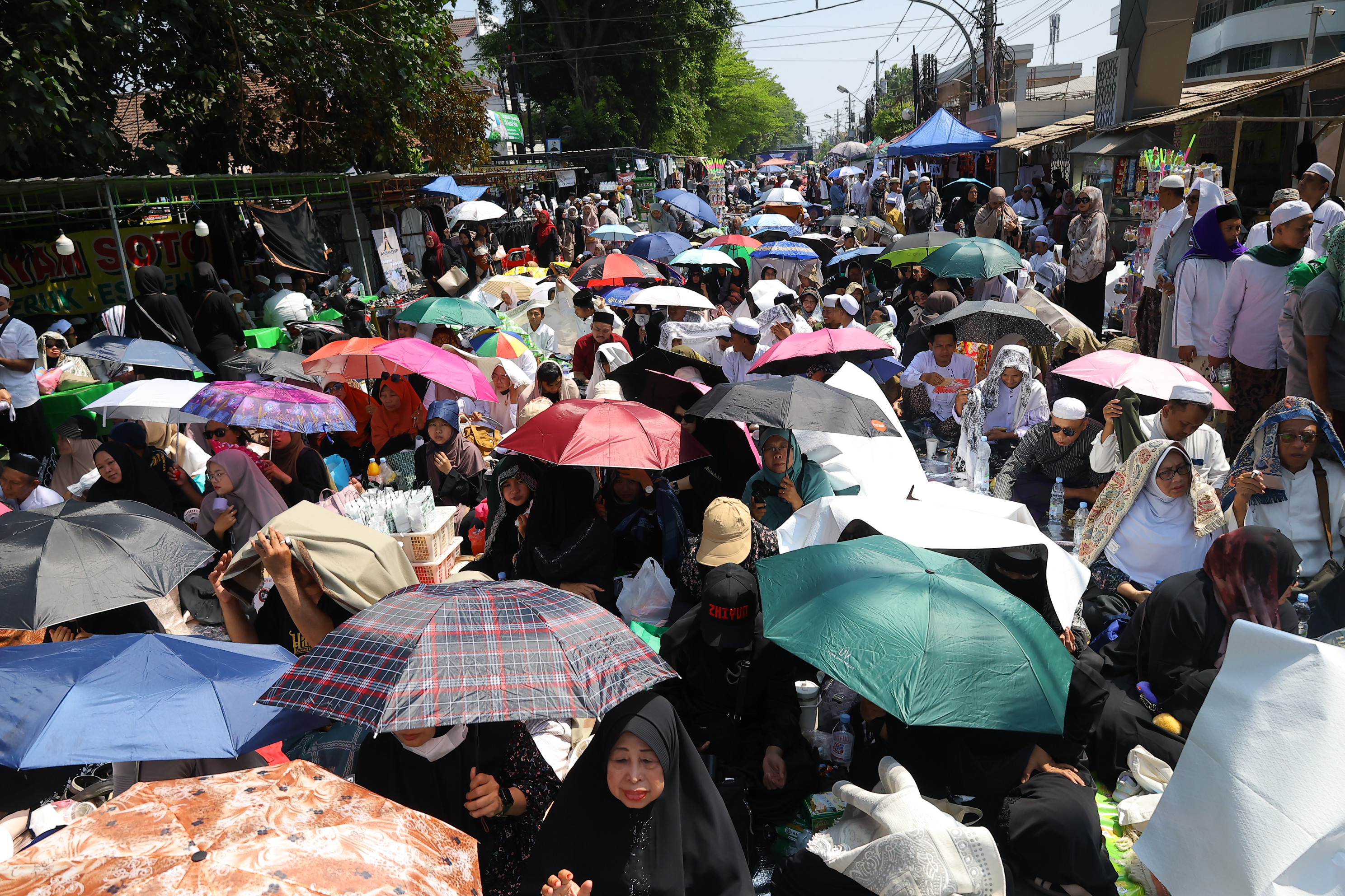 Peziarah mengenakan payung saat  menghadiri haul atau peringatan wafatnya Habib Ali bin Muhammad Al Habsyi di Pasar Kliwon, Solo, Sabtu (3/10/2026). Meskipun cuaca panas perayaan Haul ulama Habib Ali tersebut dihadiri ribuan orang yang datang dari berbagai kota di Indonesia.(Daerah/J Howi Widodo).