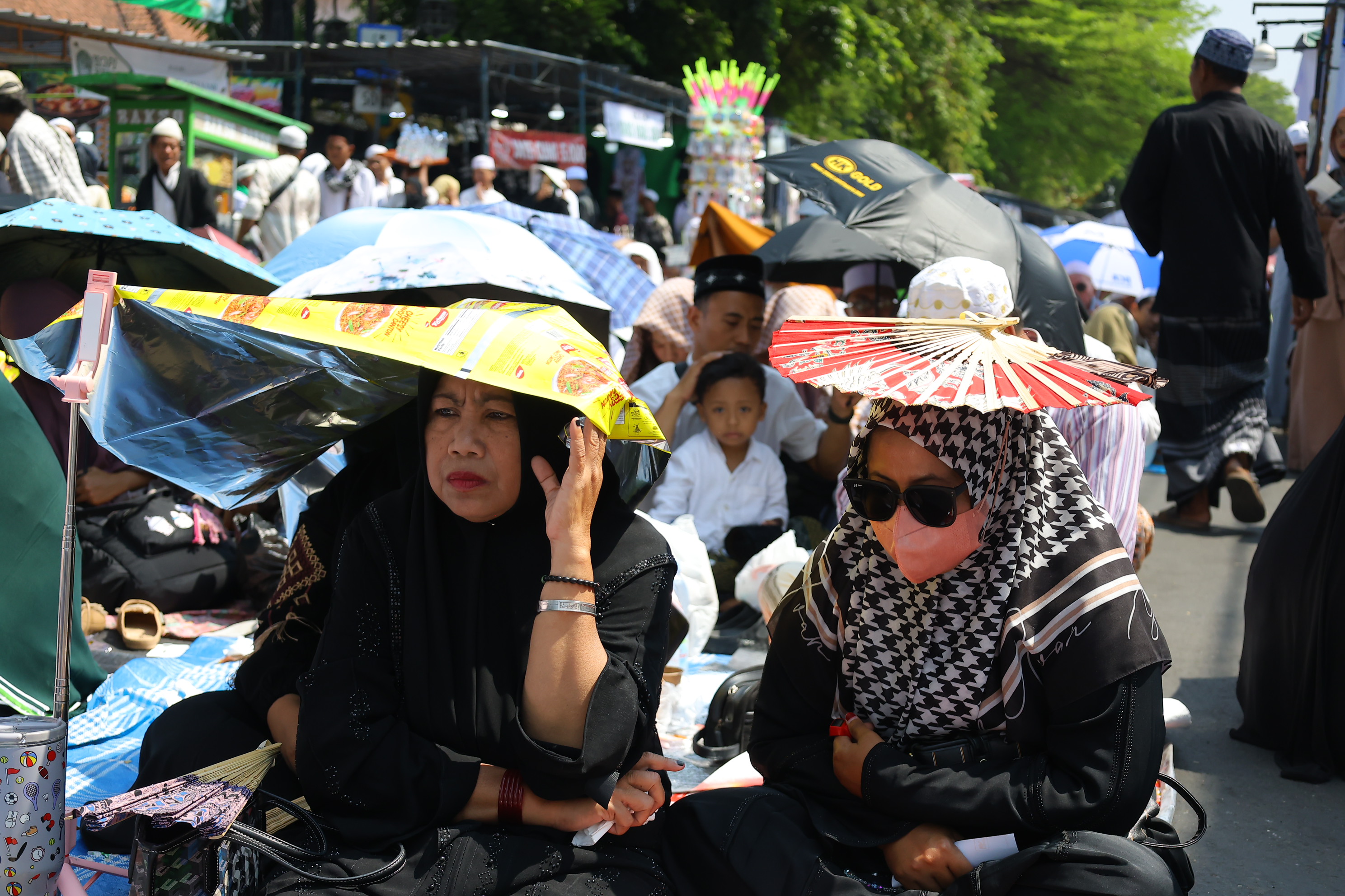 Peziarah duduk sambil mengenakan penutup kepala saat menghadiri haul atau peringatan wafatnya Habib Ali bin Muhammad Al Habsyi di Pasar Kliwon, Solo, Sabtu (3/10/2026). Meskipun cuaca panas perayaan Haul ulama Habib Ali tersebut dihadiri ribuan orang yang datang dari berbagai kota di Indonesia.(Daerah/J Howi Widodo).