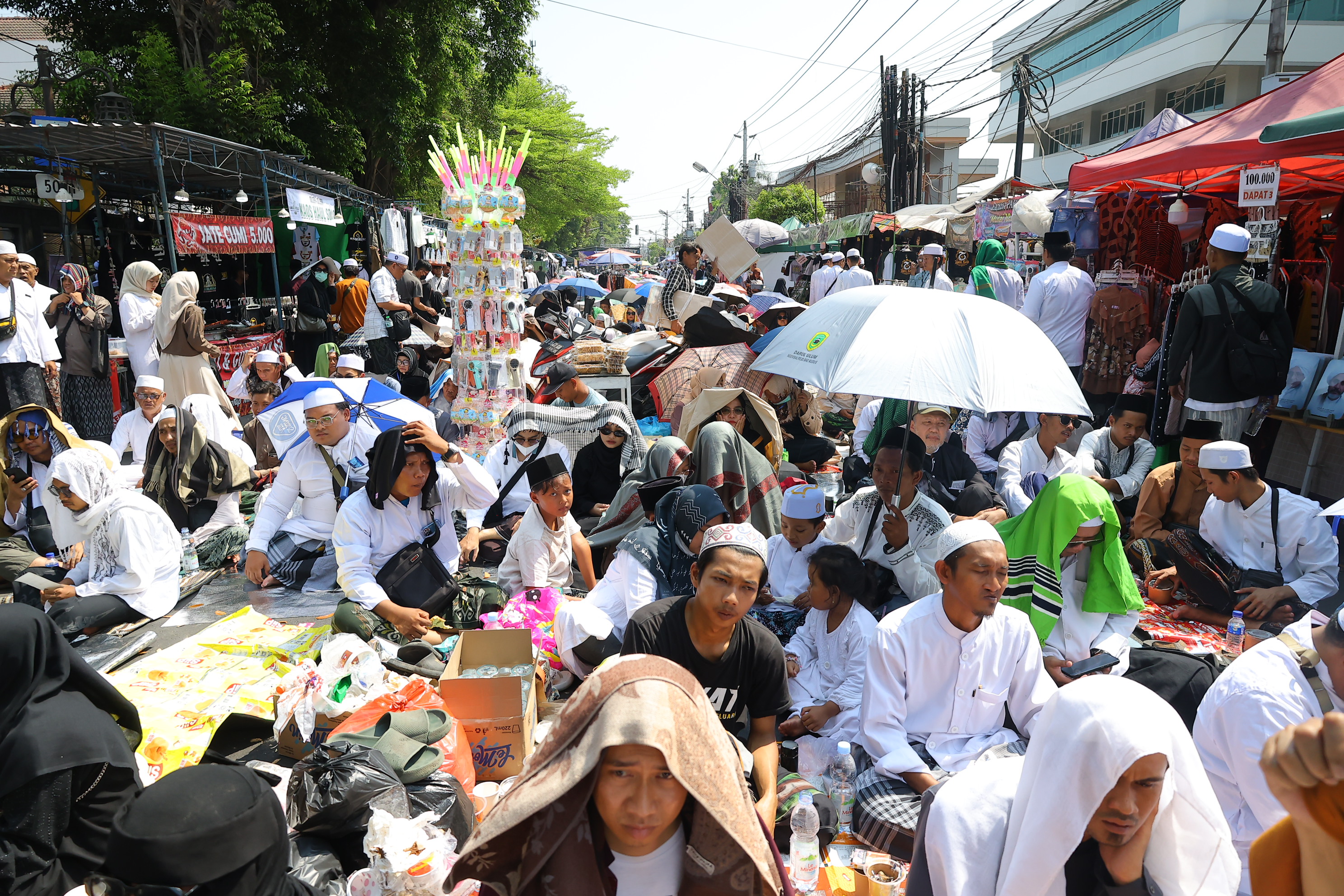 Peziarah duduk saat menghadiri haul atau peringatan wafatnya Habib Ali bin Muhammad Al Habsyi di Pasar Kliwon, Solo, Sabtu (3/10/2026). Meskipun cuaca panas perayaan Haul ulama Habib Ali tersebut dihadiri ribuan orang yang datang dari berbagai kota di Indonesia.(Daerah/J Howi Widodo).