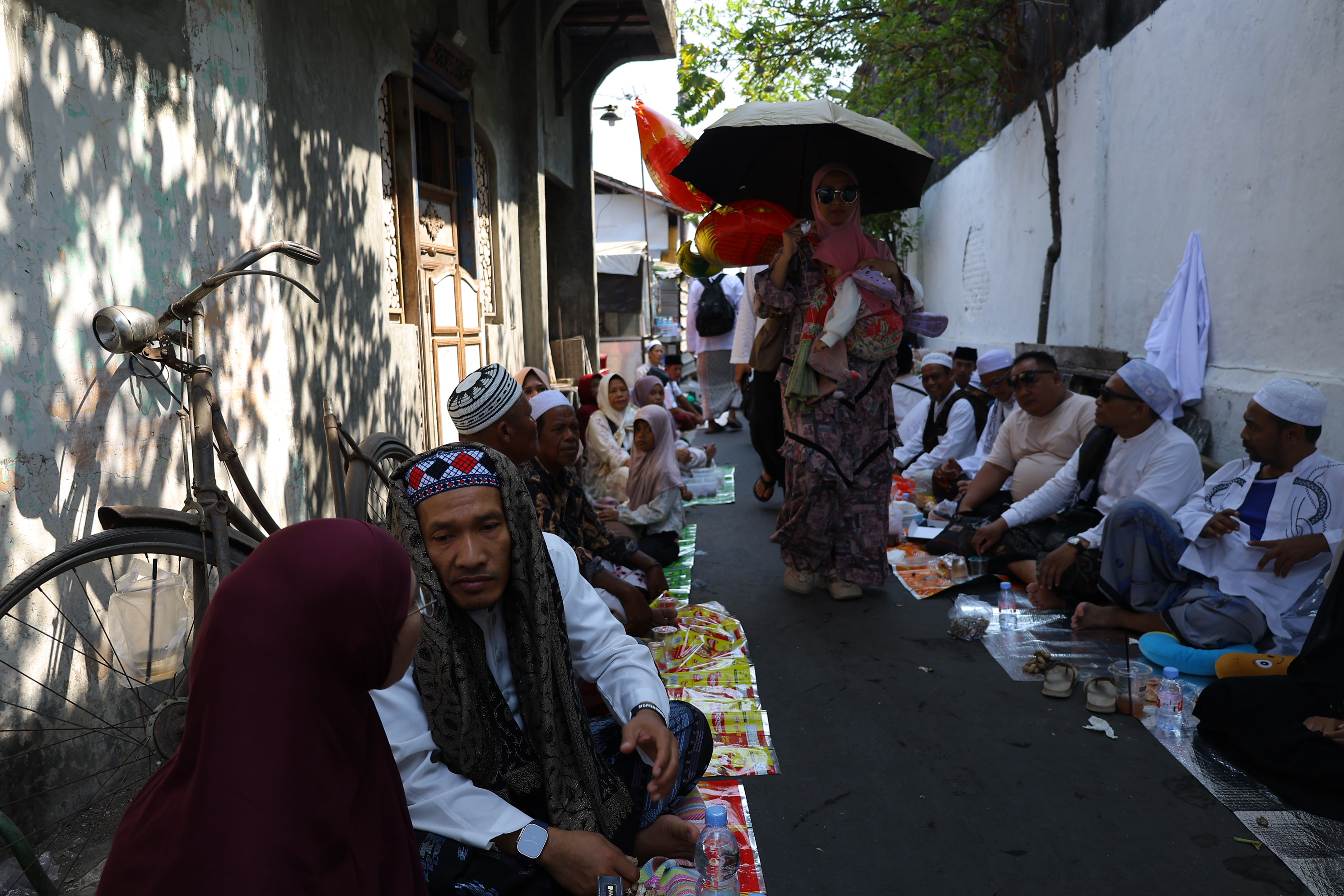 Peziarah duduk saat menghadiri haul atau peringatan wafatnya Habib Ali bin Muhammad Al Habsyi di Pasar Kliwon, Solo, Sabtu (3/10/2026). Meskipun cuaca panas perayaan Haul ulama Habib Ali tersebut dihadiri ribuan orang yang datang dari berbagai kota di Indonesia.(Daerah/J Howi Widodo).